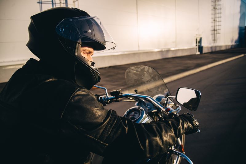 a person wearing a helmet and black leather jacket riding a motorcycle